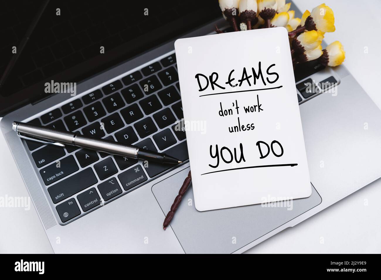 White Paper on Laptop With Inspirational Quote . Dreams Don't Work Unless You Do. Stock Photo