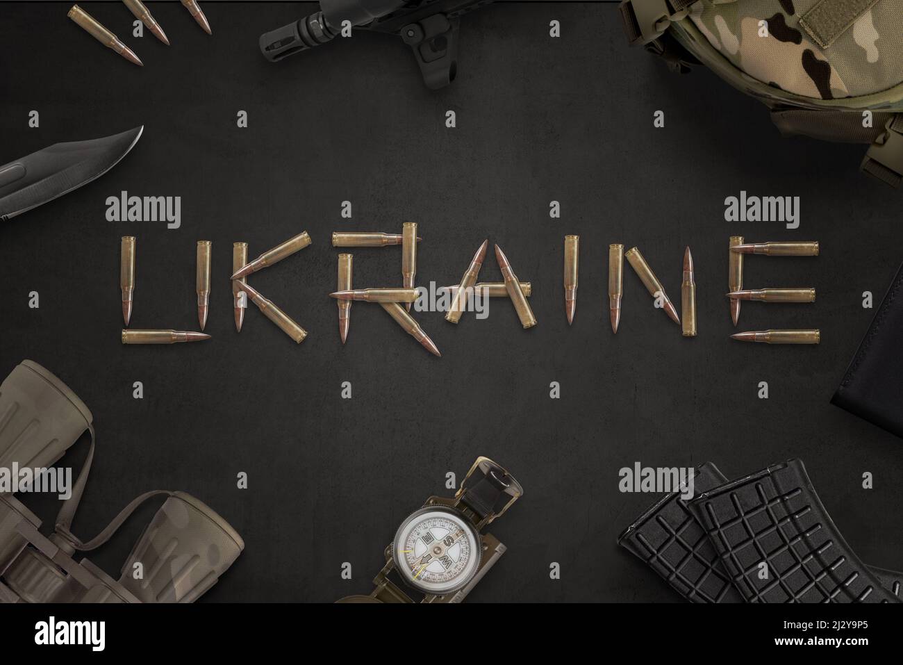 Ukraine war concept. Ukraine text written with bullets from an automatic rifle and surrounded by military equipment Stock Photo