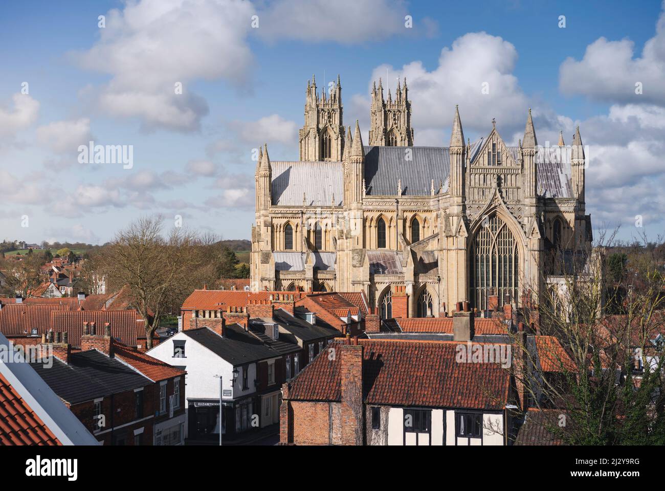 Elevated view of ancient minster (church) flanked by houses and set against blue sky with clouds view from local carpark. Beverley, UK. Stock Photo