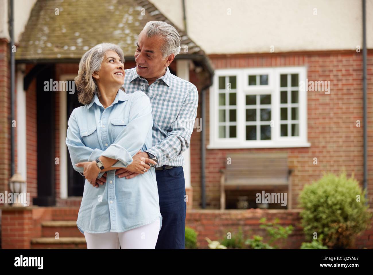 Portrait Of Mature Couple Standing In Garden In Front Of Dream Home In ...
