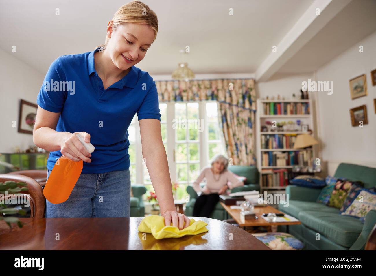 Female Home Help Cleaning House And Talking To Senior Woman Stock Photo