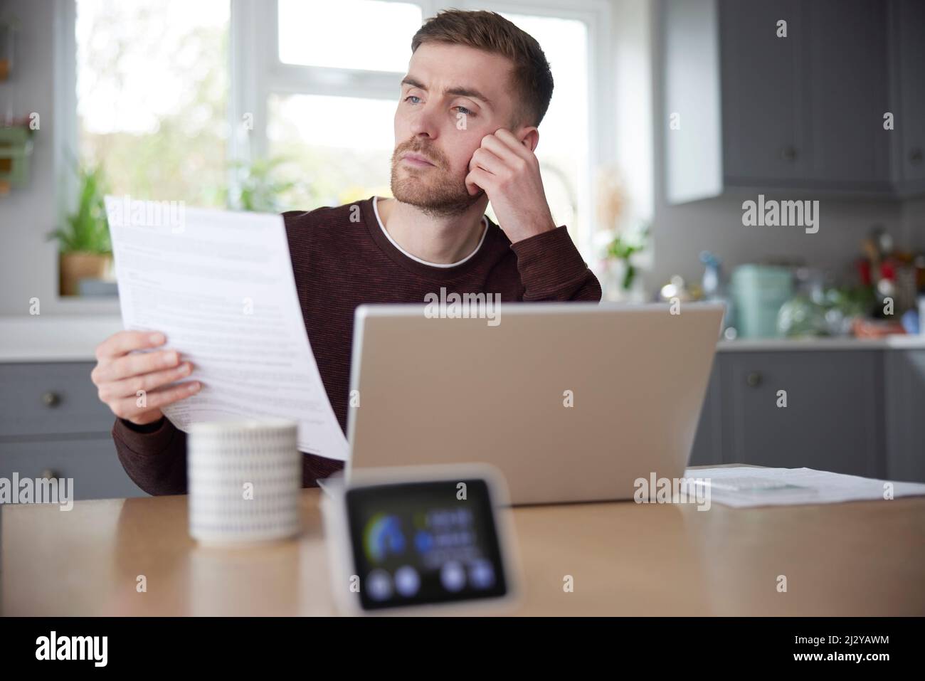 Smart Energy Meter In Kitchen Measuring Electricity And Gas Use With Man Looking At Bills Stock Photo