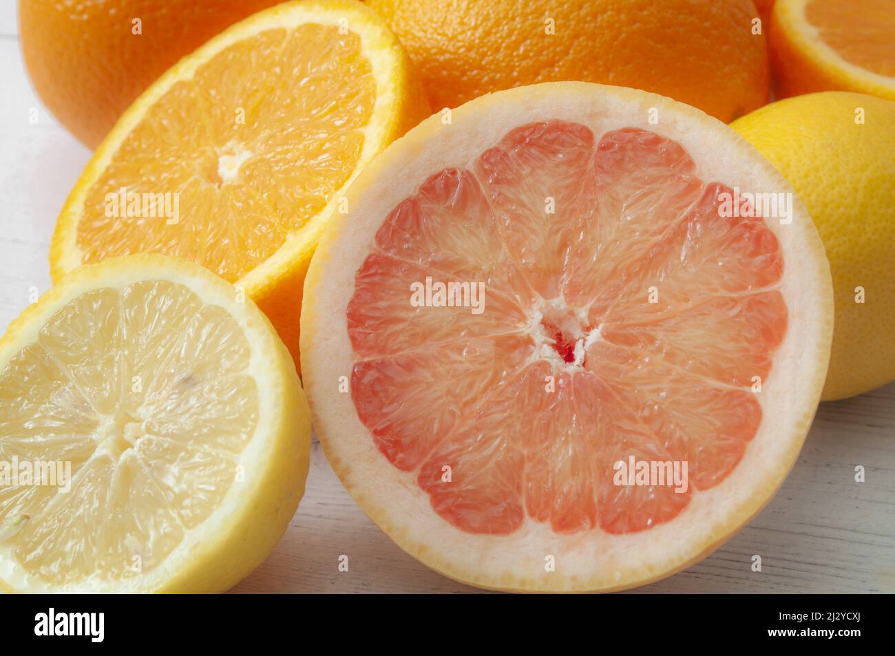 Fresh citrus fruits and food high in vitamin c concept theme with close up on a pile of mixed fruit with an orange, lemon and grapefruit sliced in hal Stock Photo