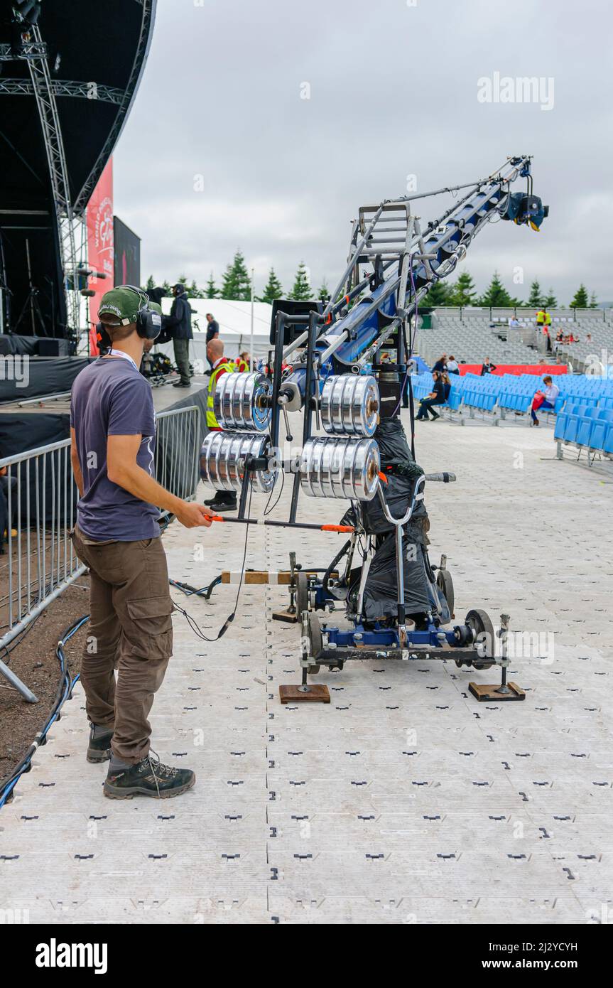 A cameraman operates a camera on the end of a boom and gimbal. Stock Photo