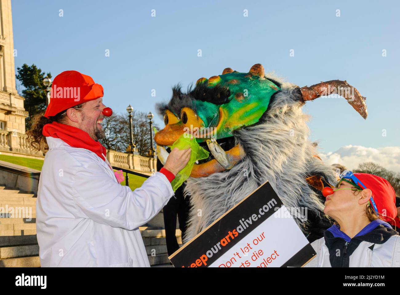 Belfast, Northern Ireland.  10th December 2007.  A man dressed as a clown wipes the nose of a large fury monster at a protest against cutting the arts budget. Stock Photo