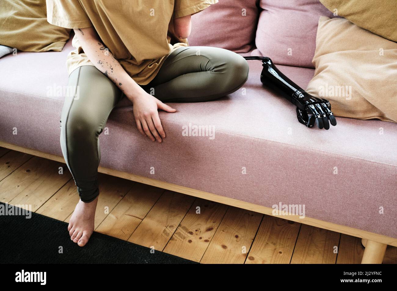 Close-up of young woman sitting on sofa and resting, she using prosthesis instead of her amputee arm Stock Photo