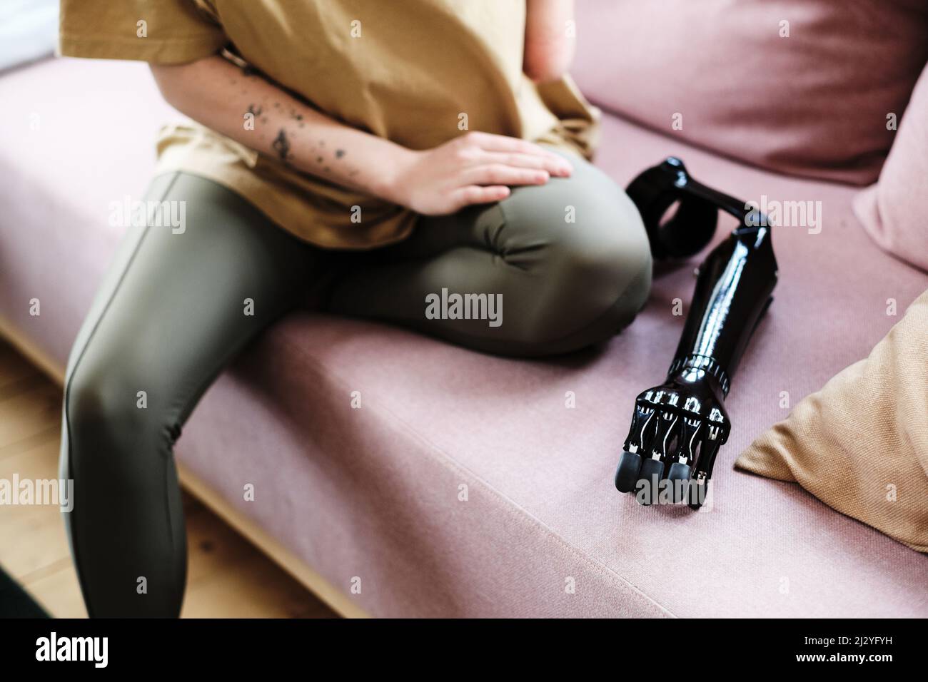 Close-up of young woman with disability sitting on sofa with prosthesis Stock Photo