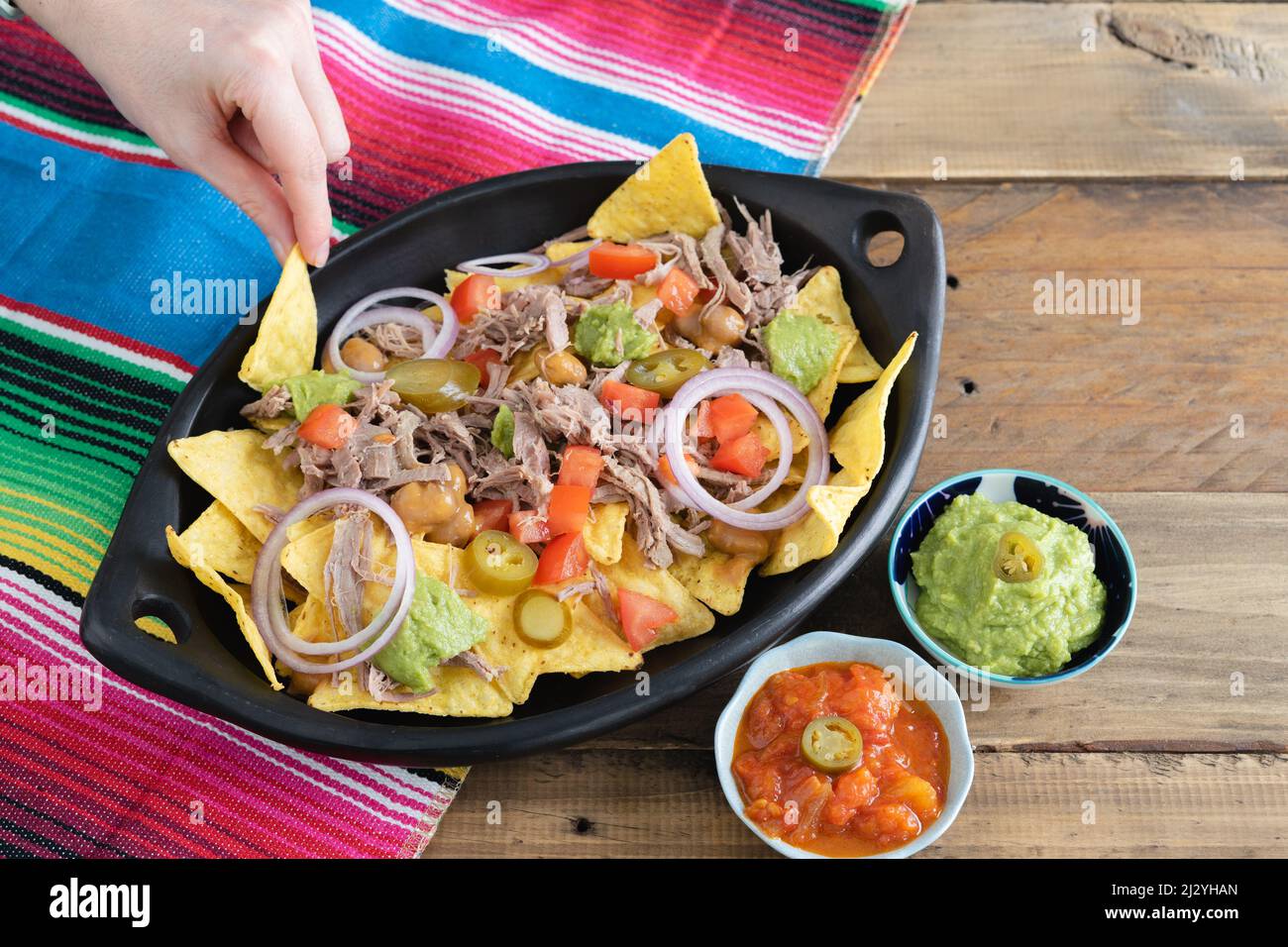 Tray of nachos with meat and mexican decoration. Bowls with salsa. Top view. Copy space. Mexican kitchen concept. Stock Photo