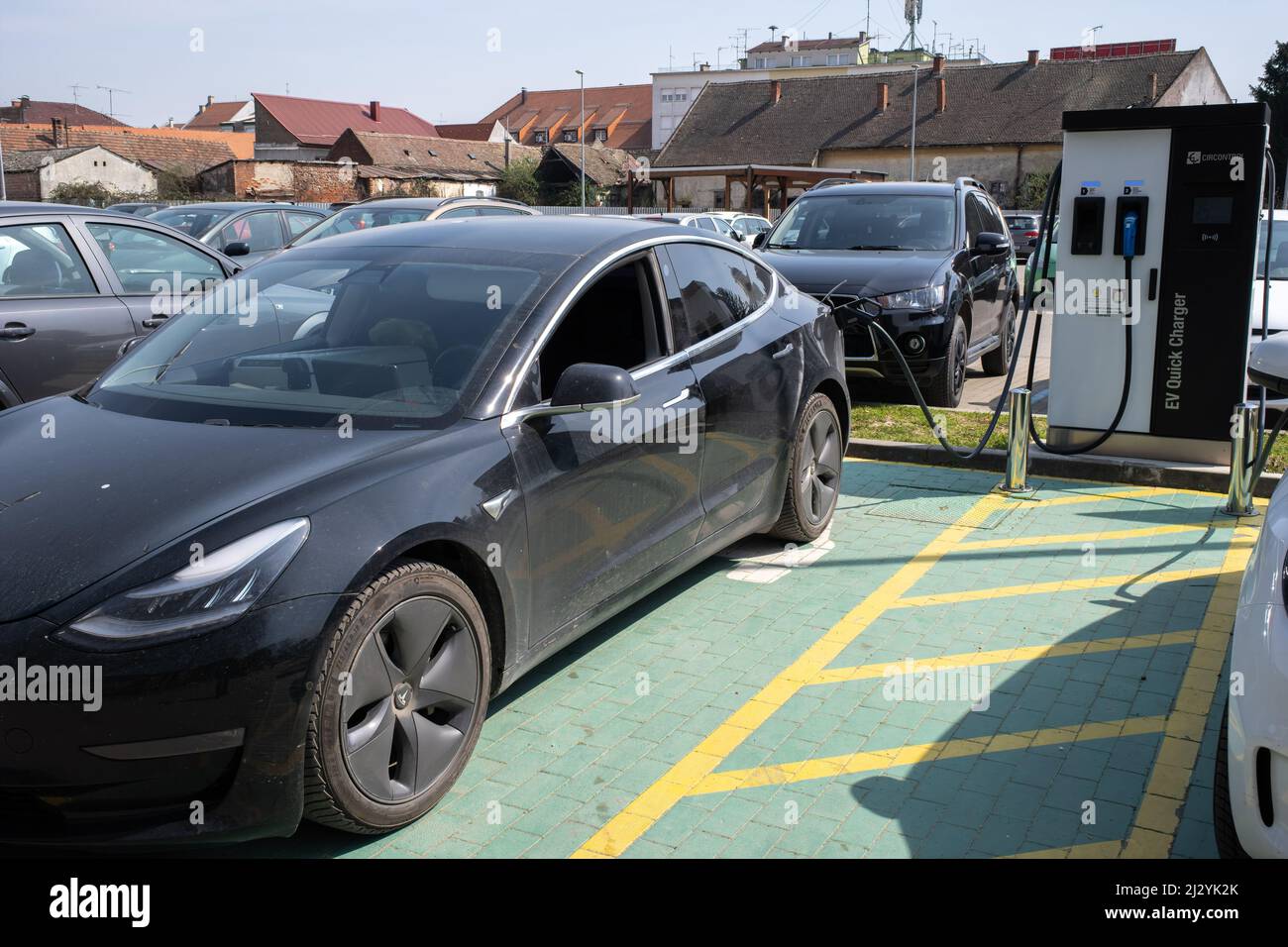 Dakovo, Croatia - March 29, 2022: A static shot of a solid black Tesla Model 3 dual motor charging at the DC charging station in a sunny spring day. Stock Photo