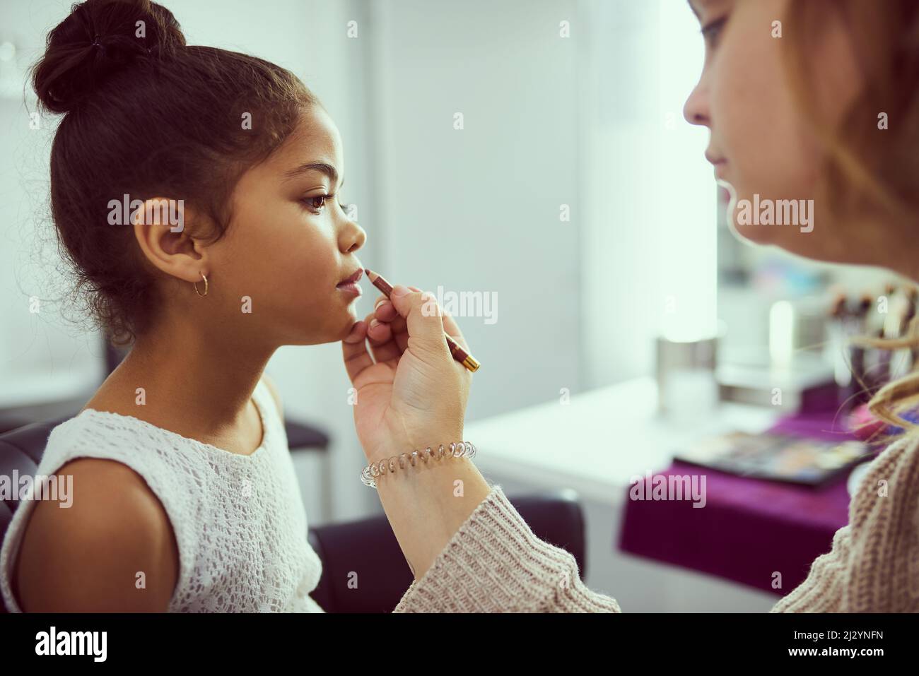 Shes a little pageant princess. Shot of a stylist applying makeup to a cute little girl in a dressing room. Stock Photo