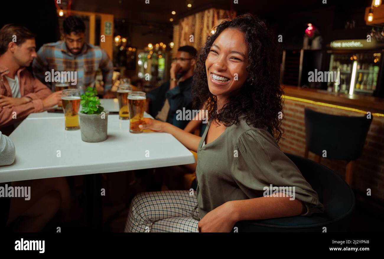 African american female laughing while enjoying drinks with friends  Stock Photo