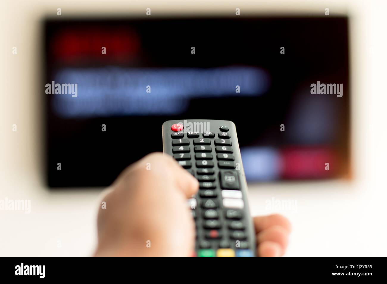 Adult male hand operating TV remote with anonymous screen on Television Stock Photo