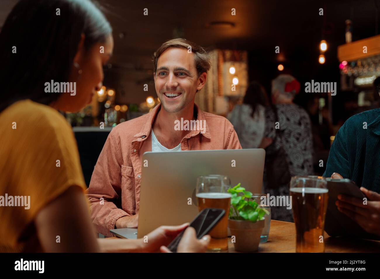 diverse colleagues out for drinks working at restaurant using laptop Stock Photo
