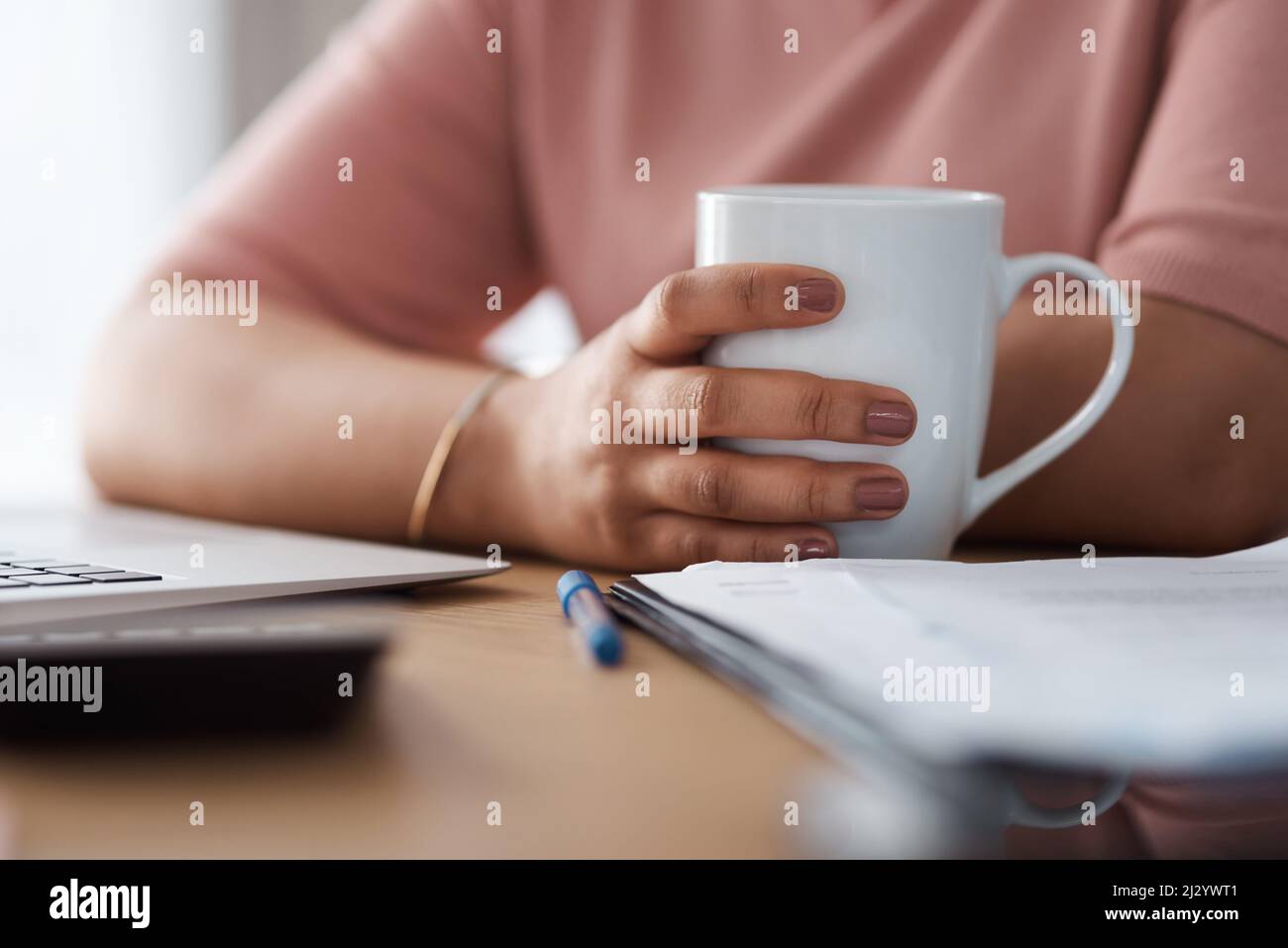 Coffee helps my brain function. Cropped shot of a woman working from home. Stock Photo