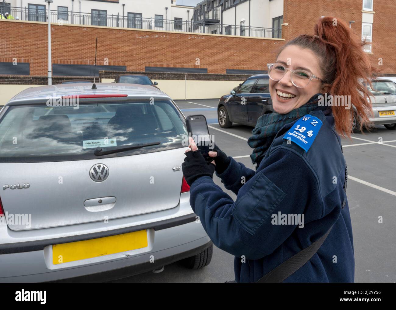 Happy at work, a parking enforcement officer at work in a car park, Farnham, Surrey, England, UK. Stock Photo