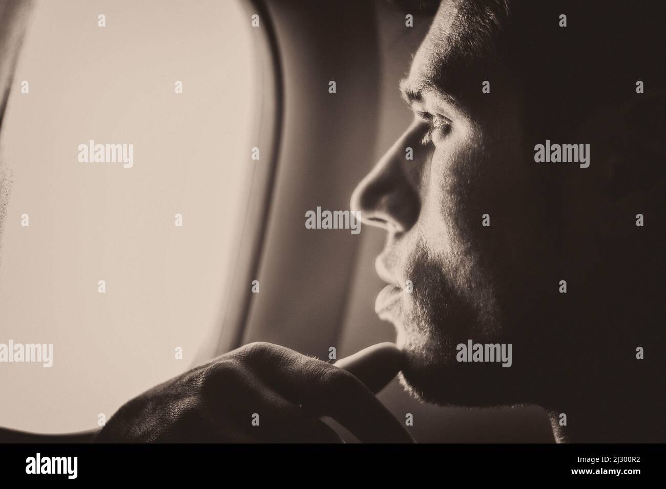 Young handsome man against plane window sitting Stock Photo
