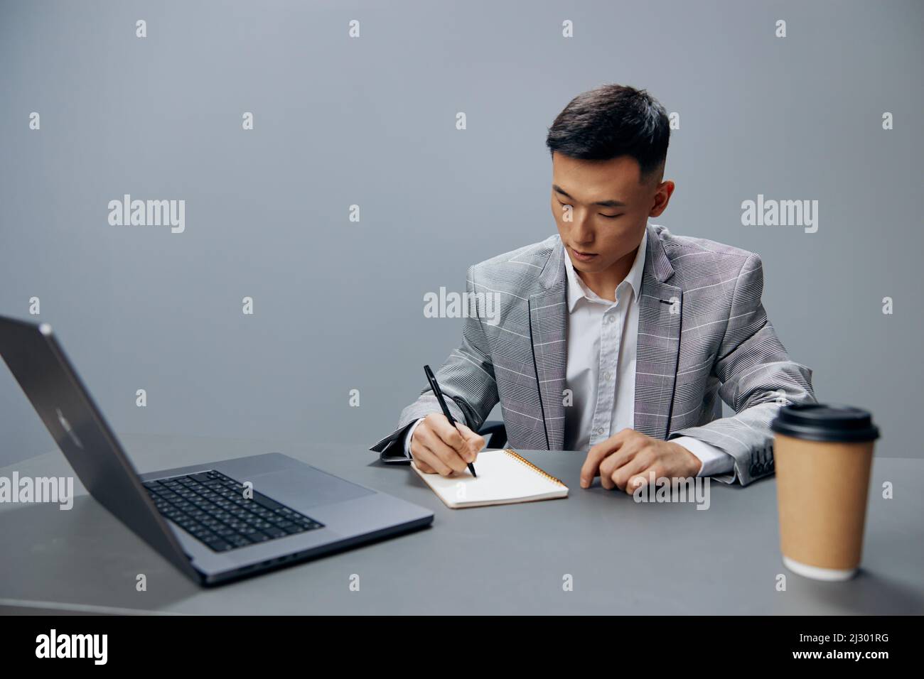 worker sitting at a desk in front of a laptop work writing in a