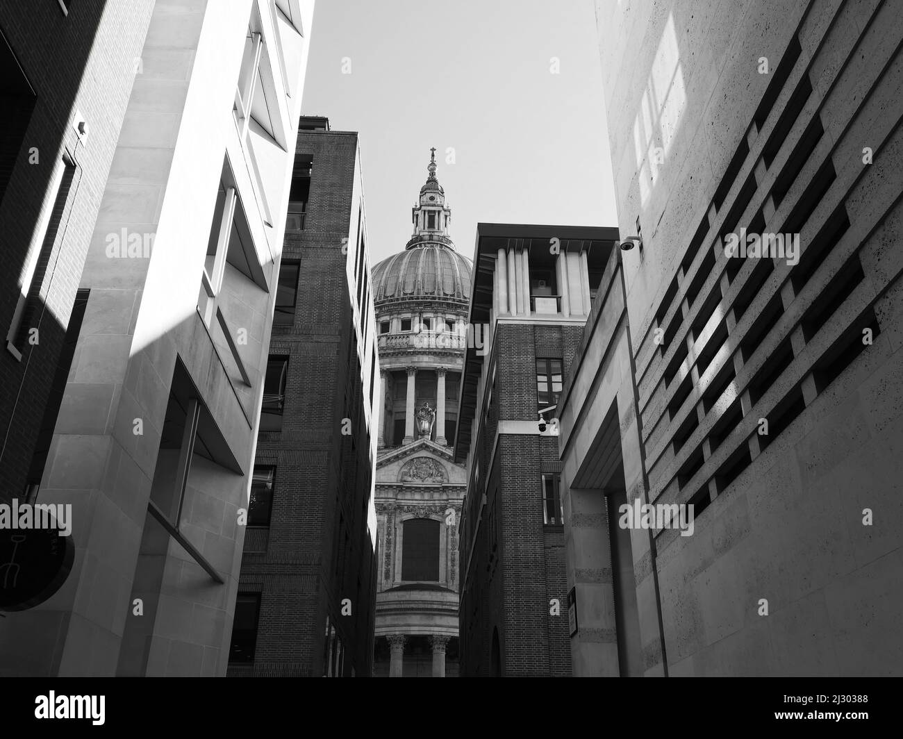 London, Greater London, England,  March 12 2022: St Pauls Cathedral dome as seen through side streets. Monochrome. Stock Photo