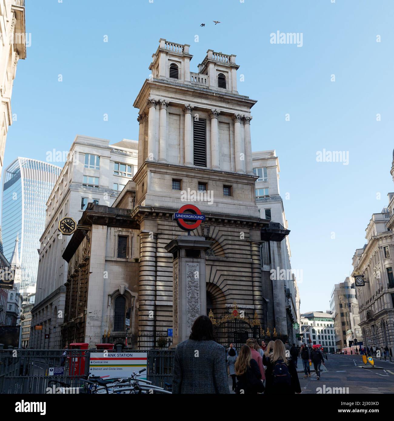 London, Greater London, England,  March 12 2022: Pedestrian looking up at birds flying near Bank Tube station in the City of London. Stock Photo