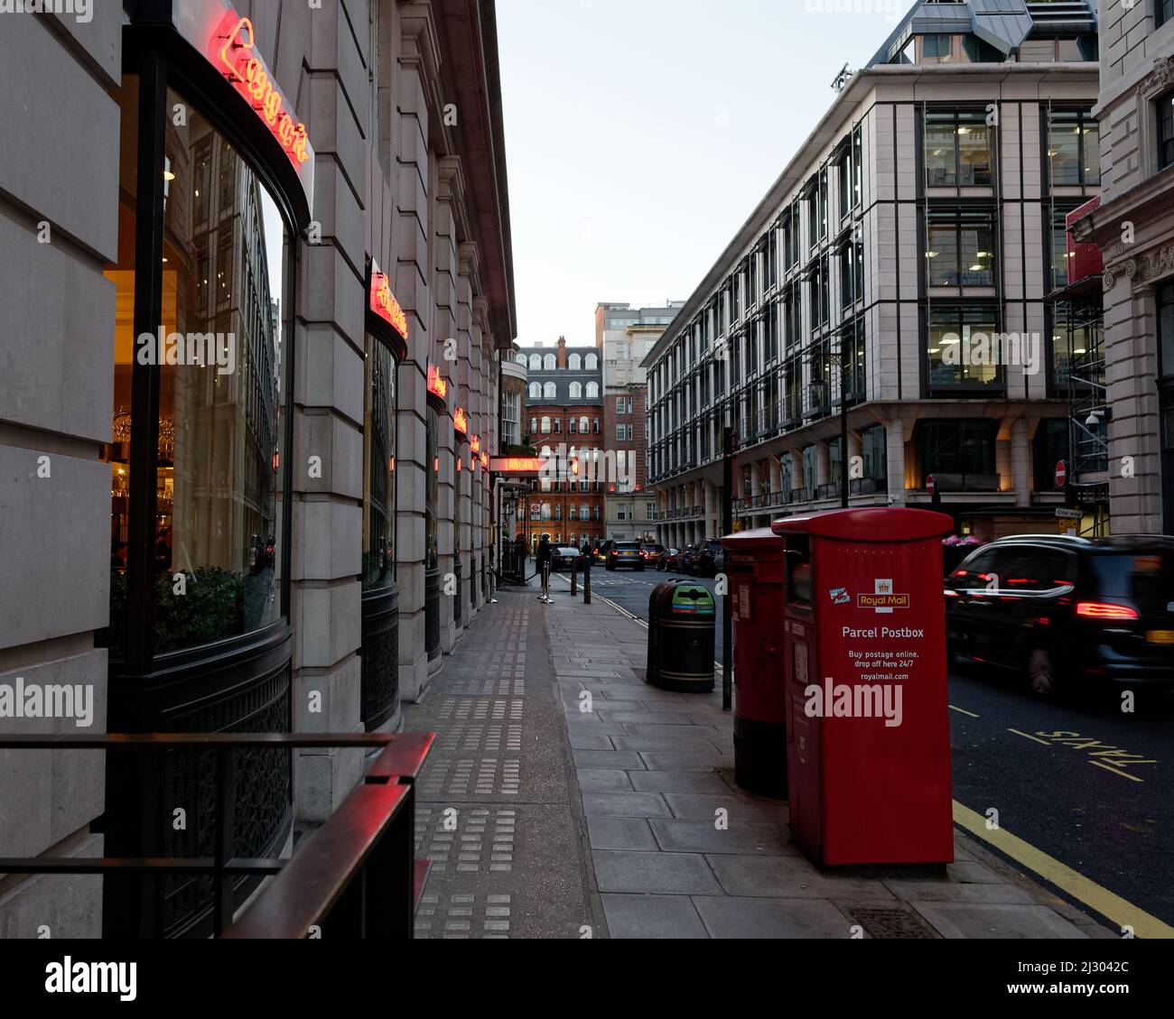 Street off Piccadilly in the evening with neon signs reflected in a car and post boxes in the foreground. London Stock Photo