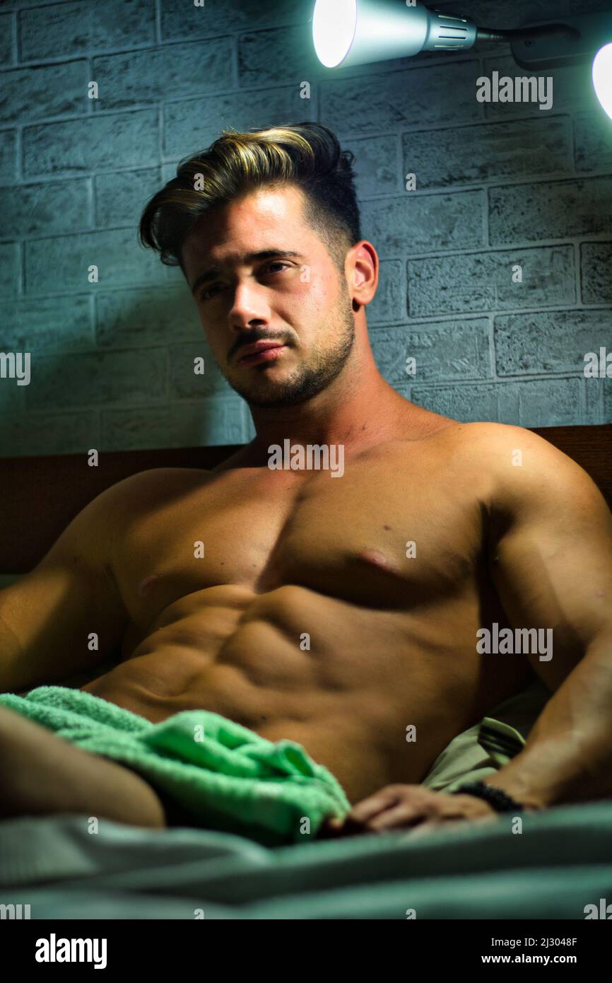 Shirtless sexy male model lying alone on his bed Stock Photo