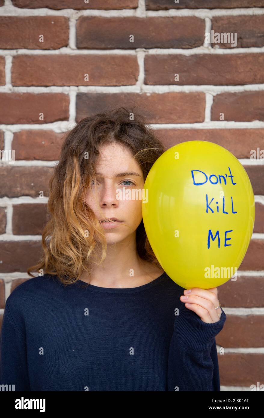 adult desperate girl with a yellow balloon with the inscriptions dont kill me. Ukrainians against the war. Feelings of fear, despair, drawing attentio Stock Photo