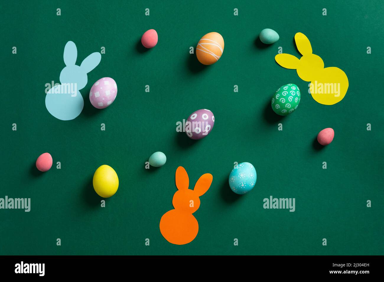 Beautiful different colorful Easter eggs with bunnies of paper on green Stock Photo