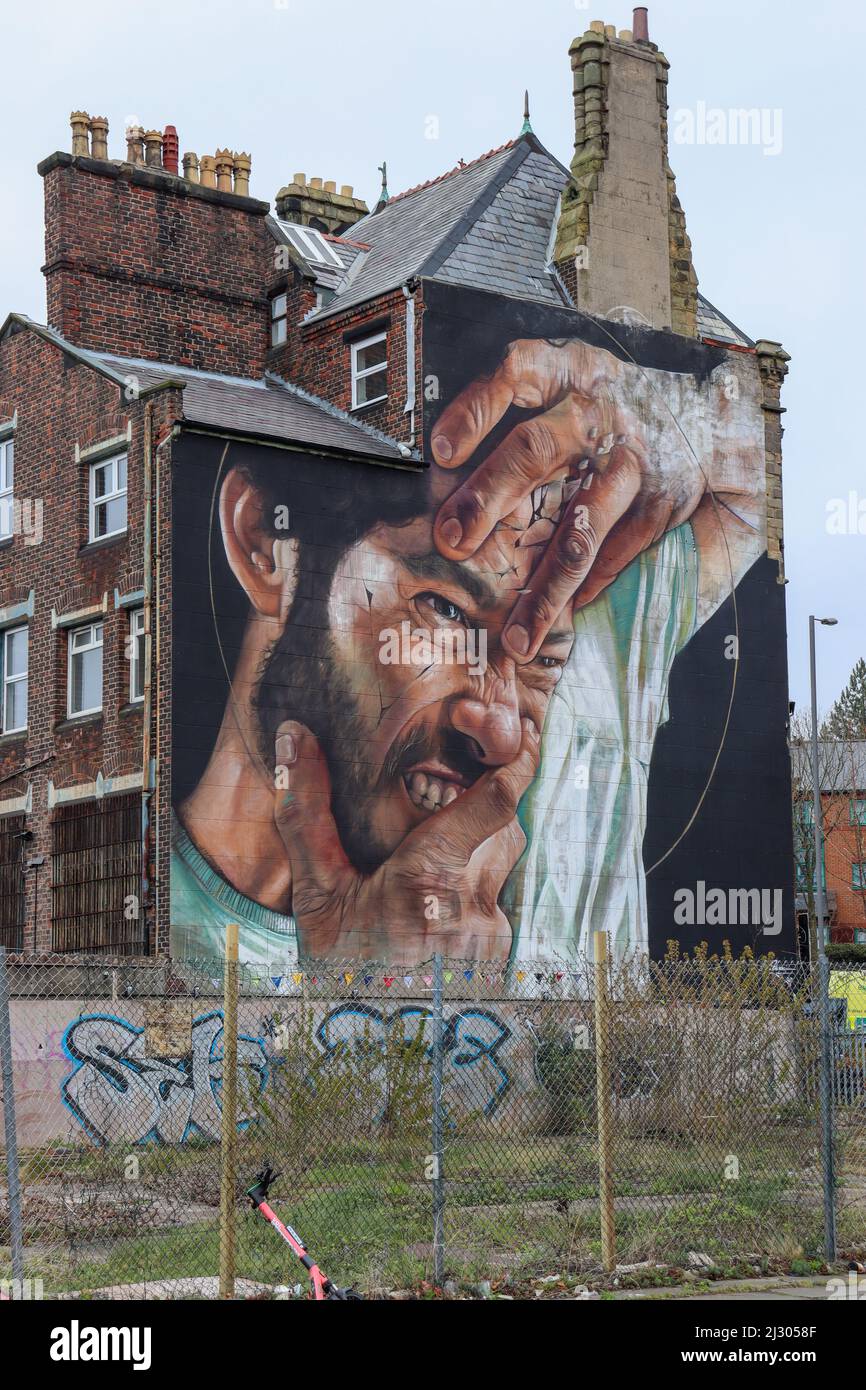 Mural on the side of a building a mans face, cracking and in pain Stock Photo