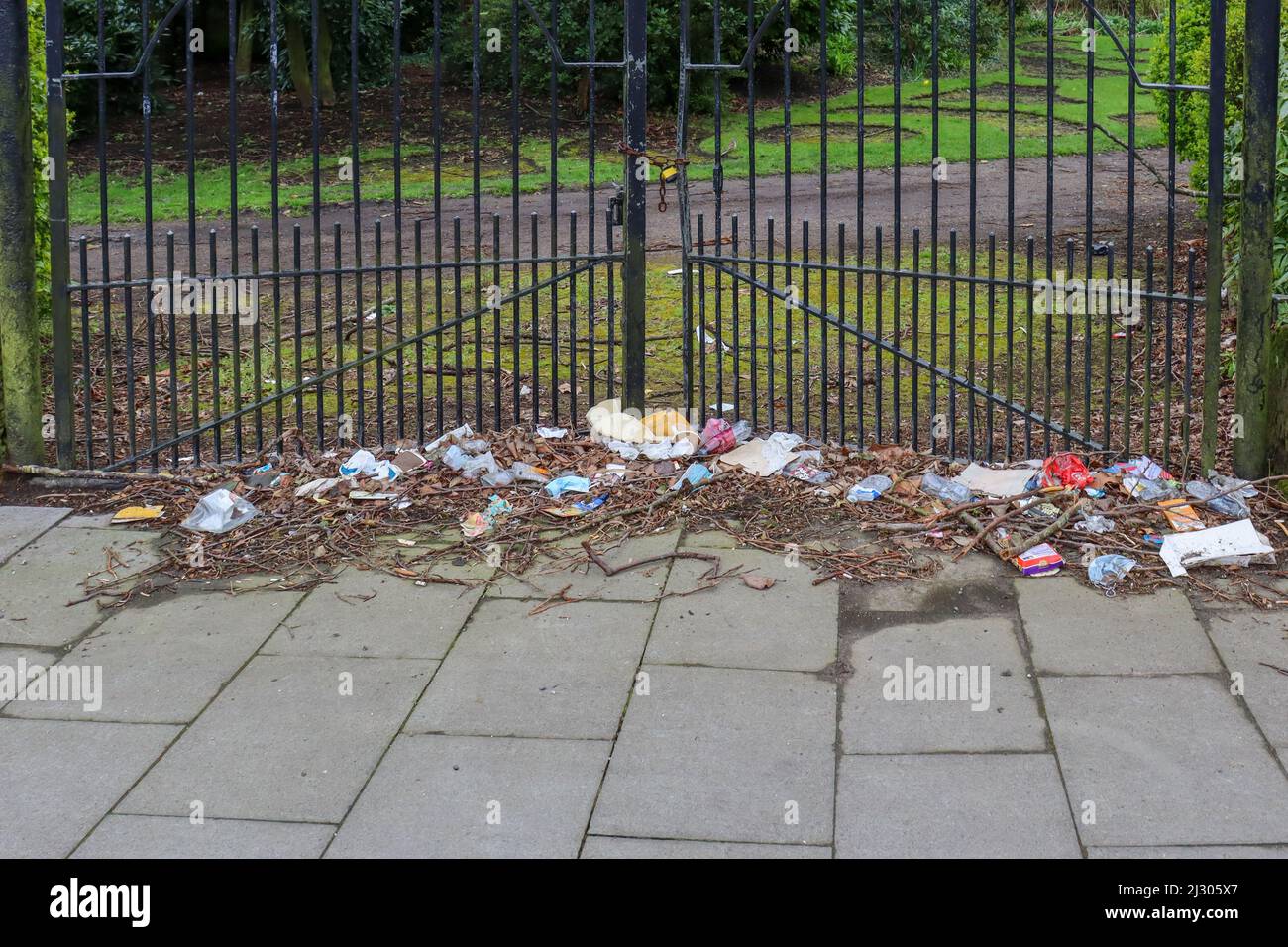 Mixed litter up against the gates of a park Stock Photo