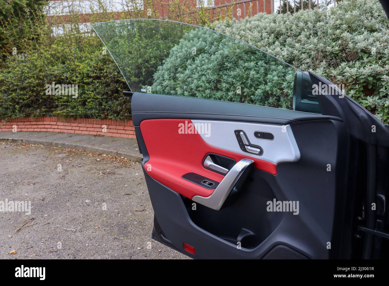 Open pillarless car door, with red leather insert, chrome seat controls and window controls Stock Photo