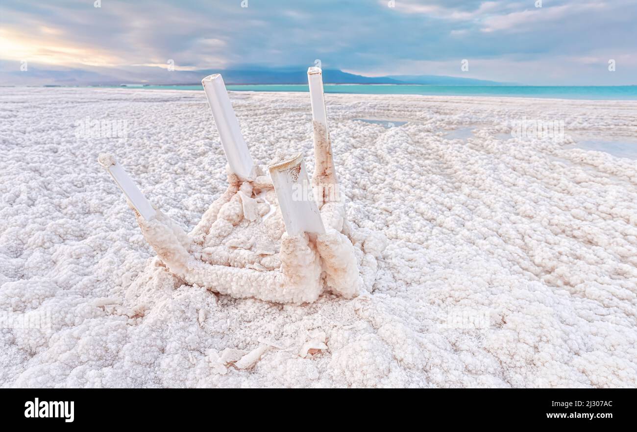 Small plastic chair completely covered with crystalline salt on shore of dead sea, closeup detail Stock Photo