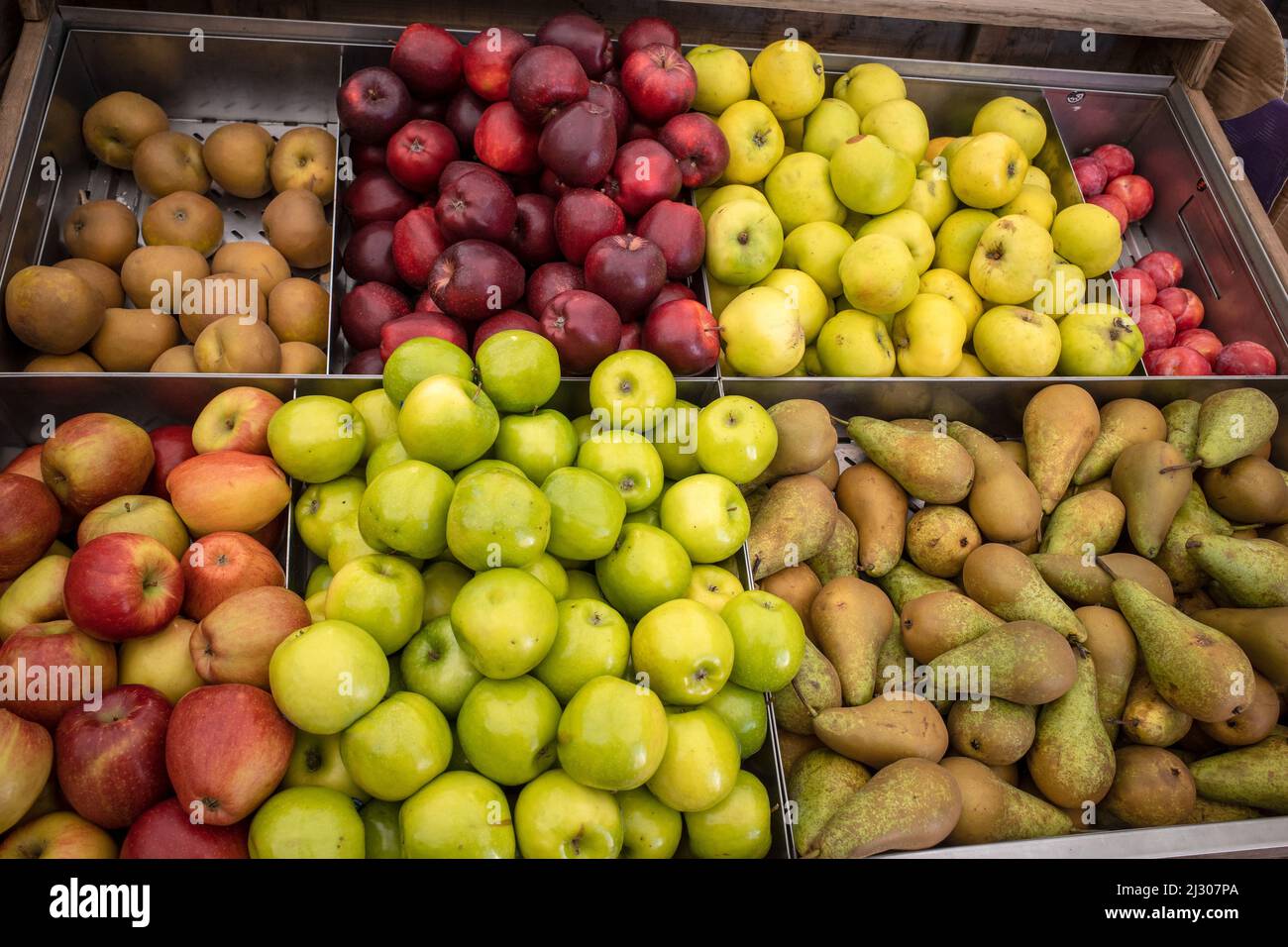 A display of various types green and red of apples and pears in boxes at a grocery store. Stock Photo