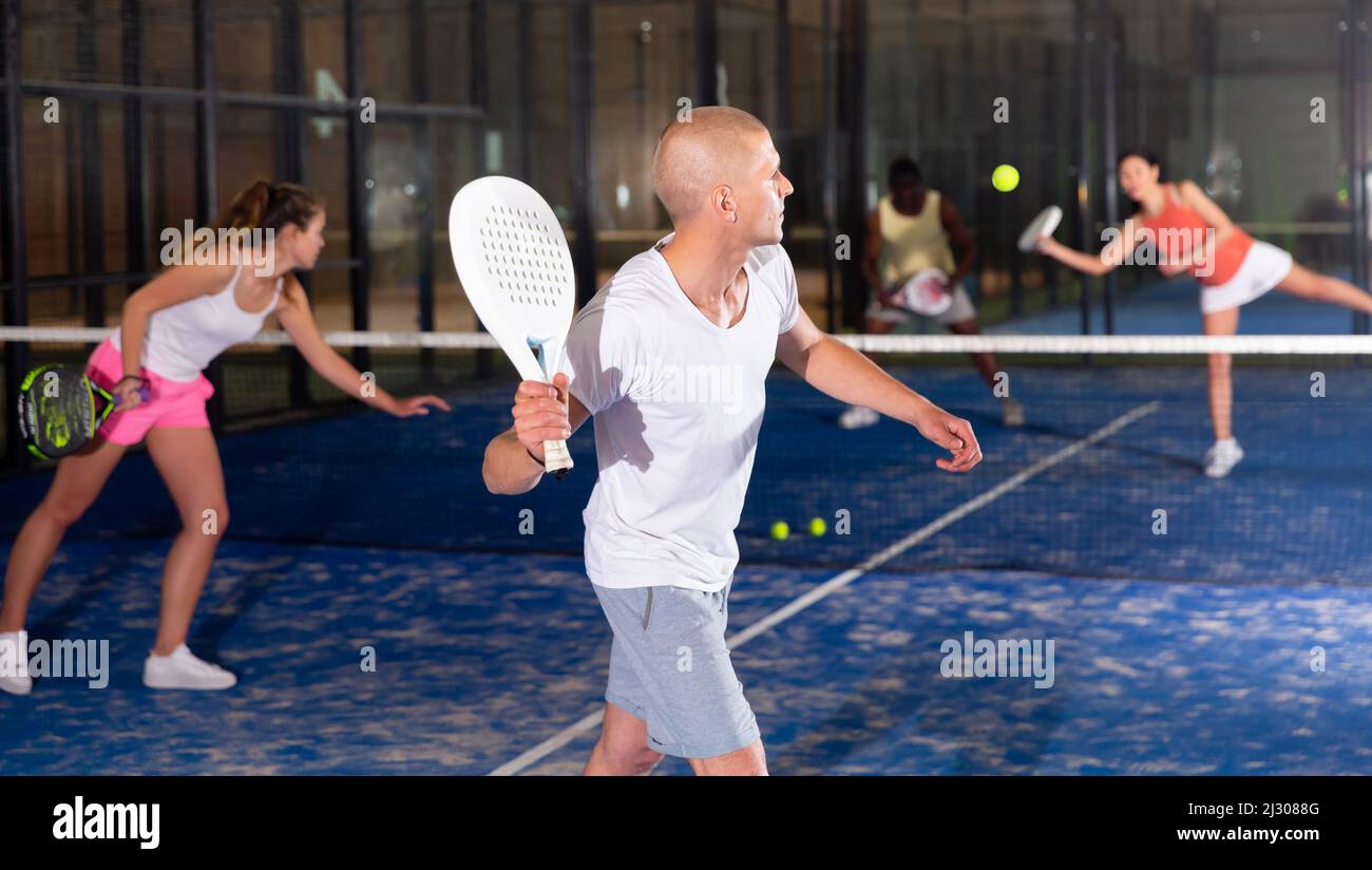 Padel player playing padel in a padel court indoor behind net Stock ...