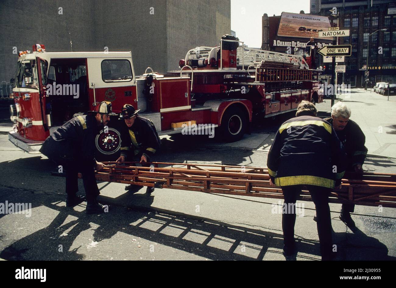 Feuerwehrmänner des San Francisco Fire Department verladen eine Leiter auf ihr Drehleiter-Fahrzeug. - Firefighters of the San Francisco Fire Department loading a ladder on their tiller truck. Stock Photo