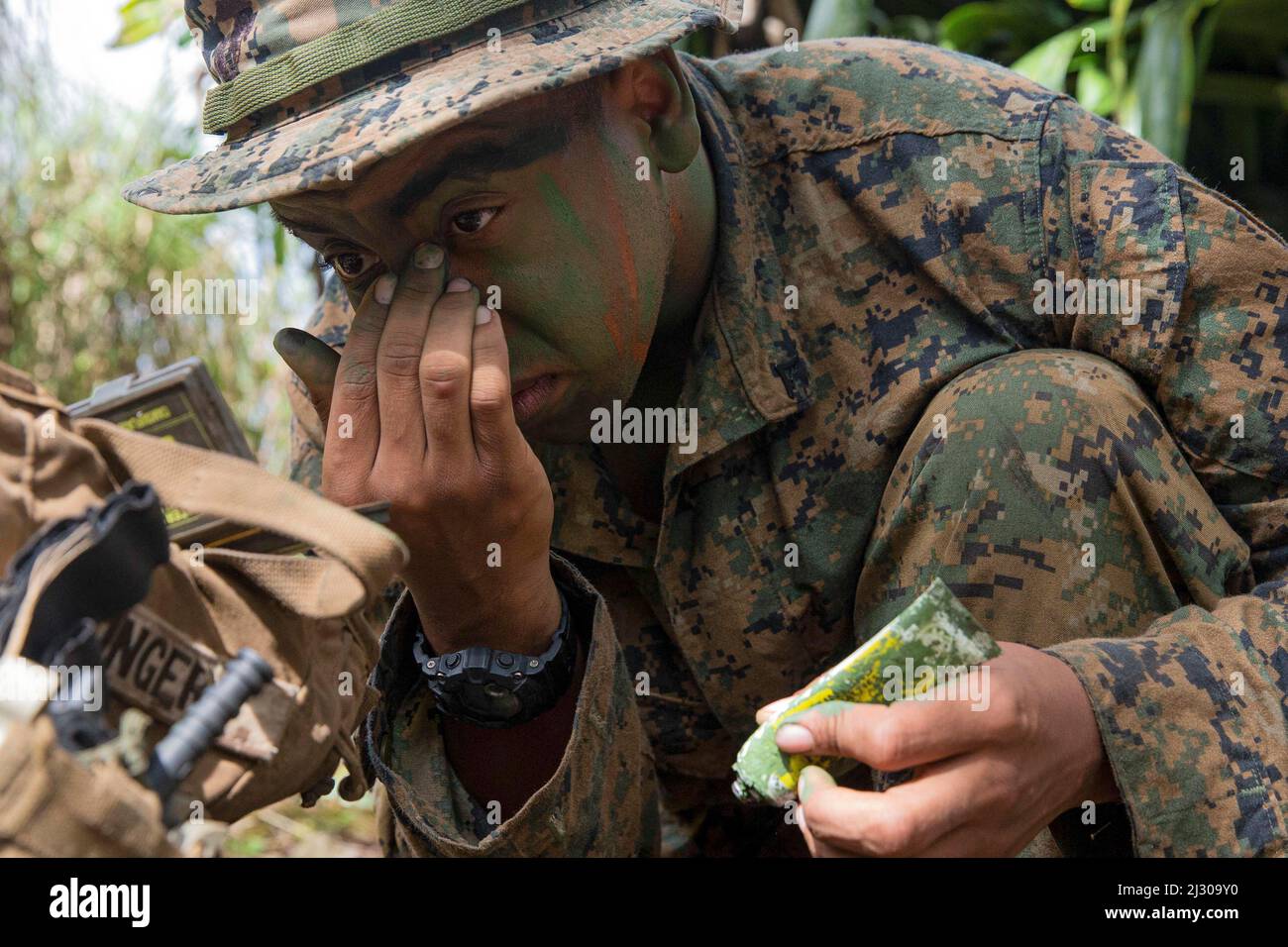 Guam. 22nd Mar, 2022. U.S. Marine Corps Lance Cpl. Isaiah Ellinger, an infantry Marine with Battalion Landing Team 1/5, 31st Marine Expeditionary Unit (MEU), applies camo paint during an experimental jungle training exercise, Naval Base Guam, Guam, Mar. 20, 2022. Exercise Noble Arashi is part of 31st MEU's Noble Series of exercises which are used to validate or invalidate the Family of Naval Concepts, develop techniques and procedures for the employment of MEU assets in support of sea denial and fleet maneuver, and inform future force design and experimentation efforts. The 31st MEU is ope Stock Photo