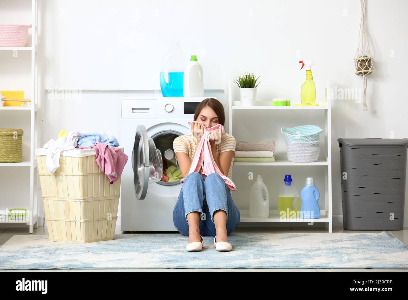 Beautiful housewife smelling clean clothes after washing at home Stock