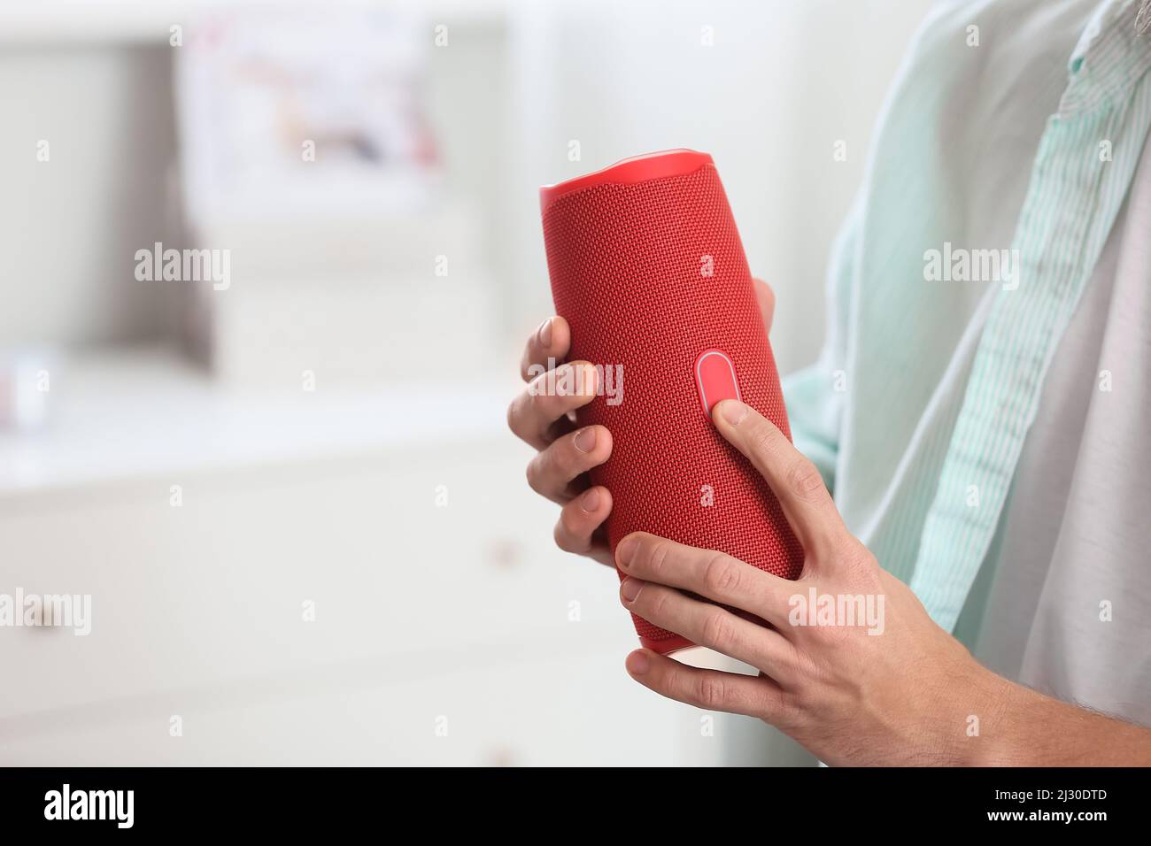 Man turning on wireless portable speaker in room, closeup Stock Photo ...