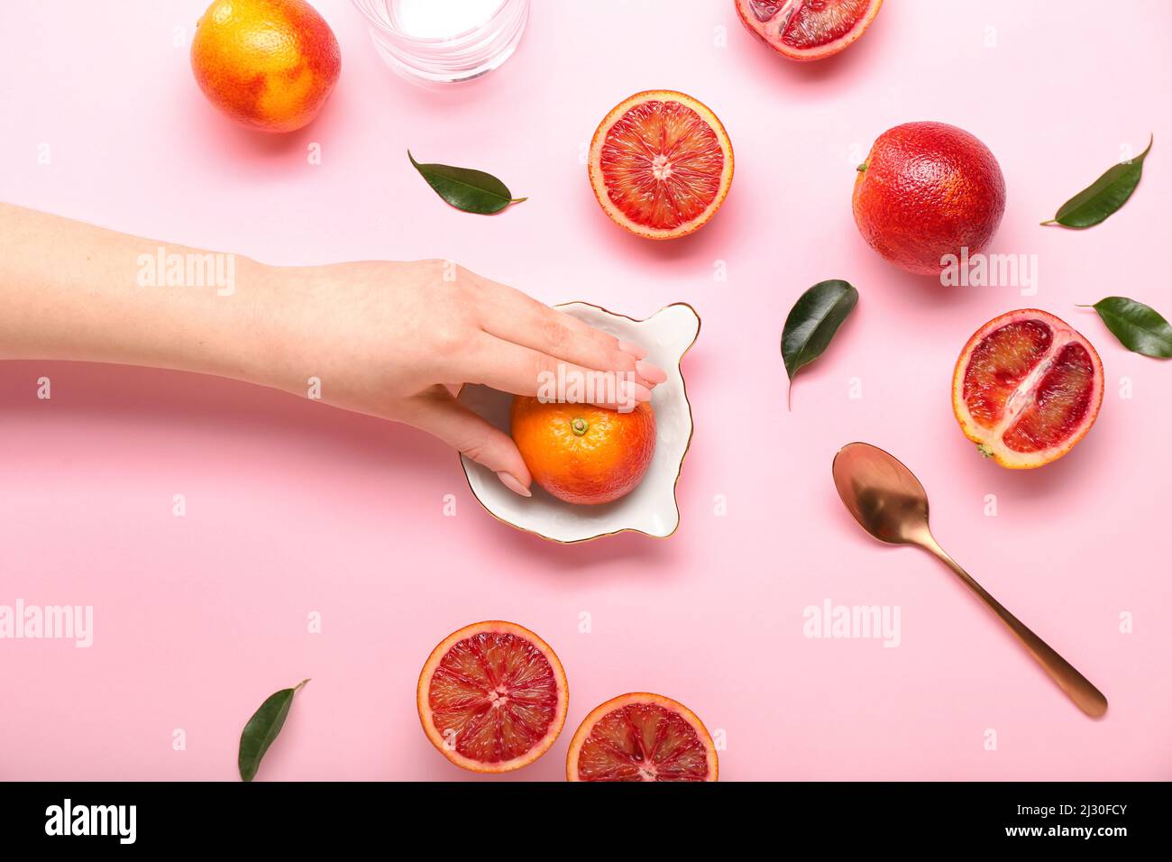 Woman squeezing fresh grapefruit on pink background Stock Photo