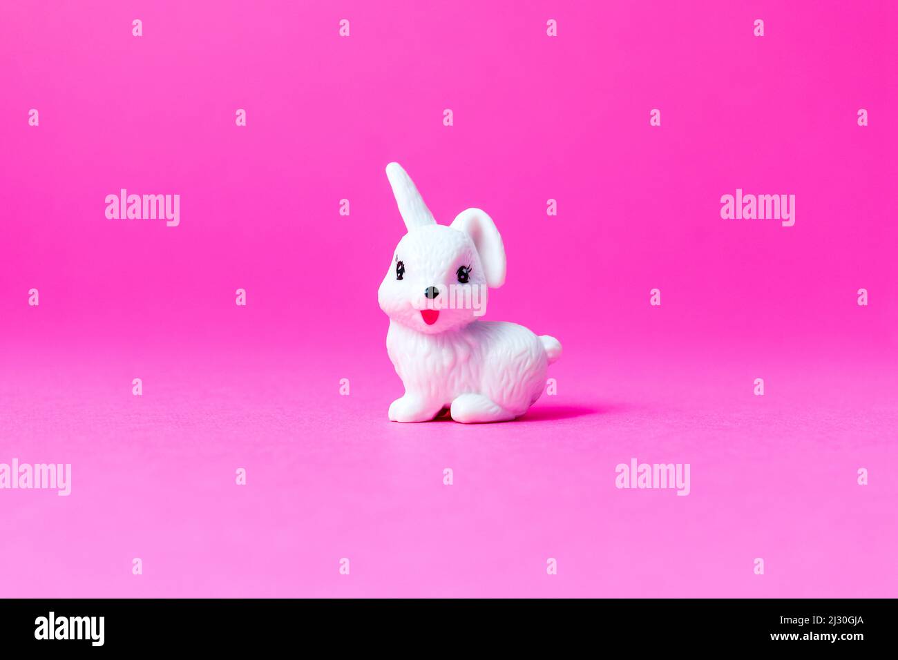 Little white Easter rabbit sitting on pink background Stock Photo - Alamy