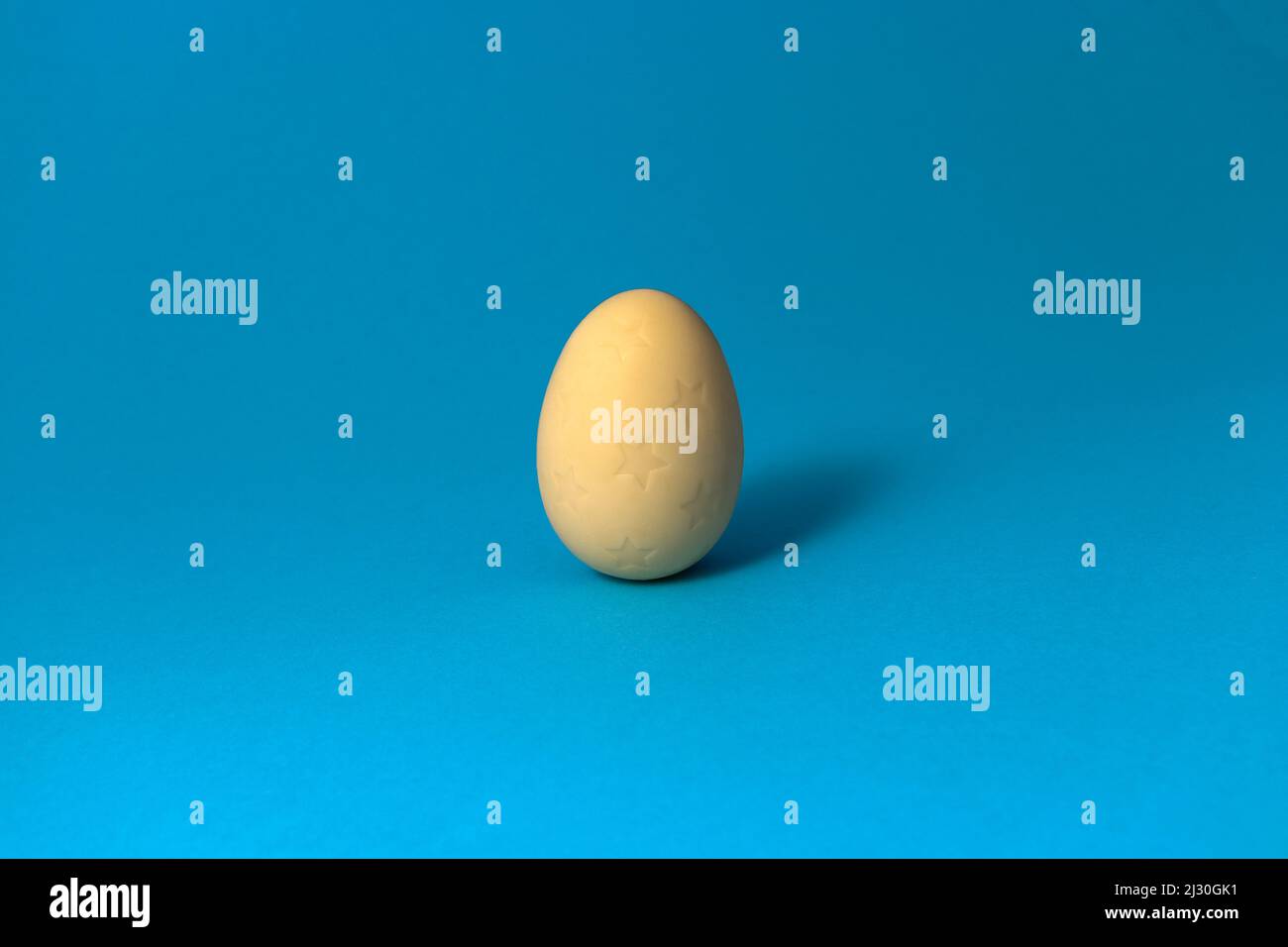 White chocolate Easter egg on blue pastel background. Close up. Stock Photo