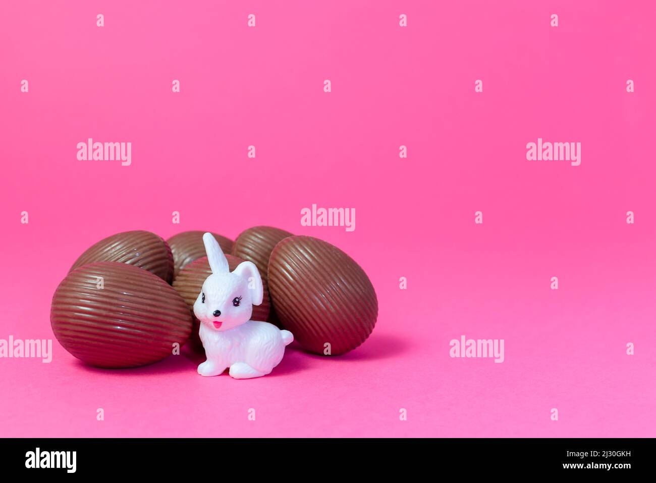 White rabbit watching over bunch of chocolate eggs Easter Holiday Concept Stock Photo