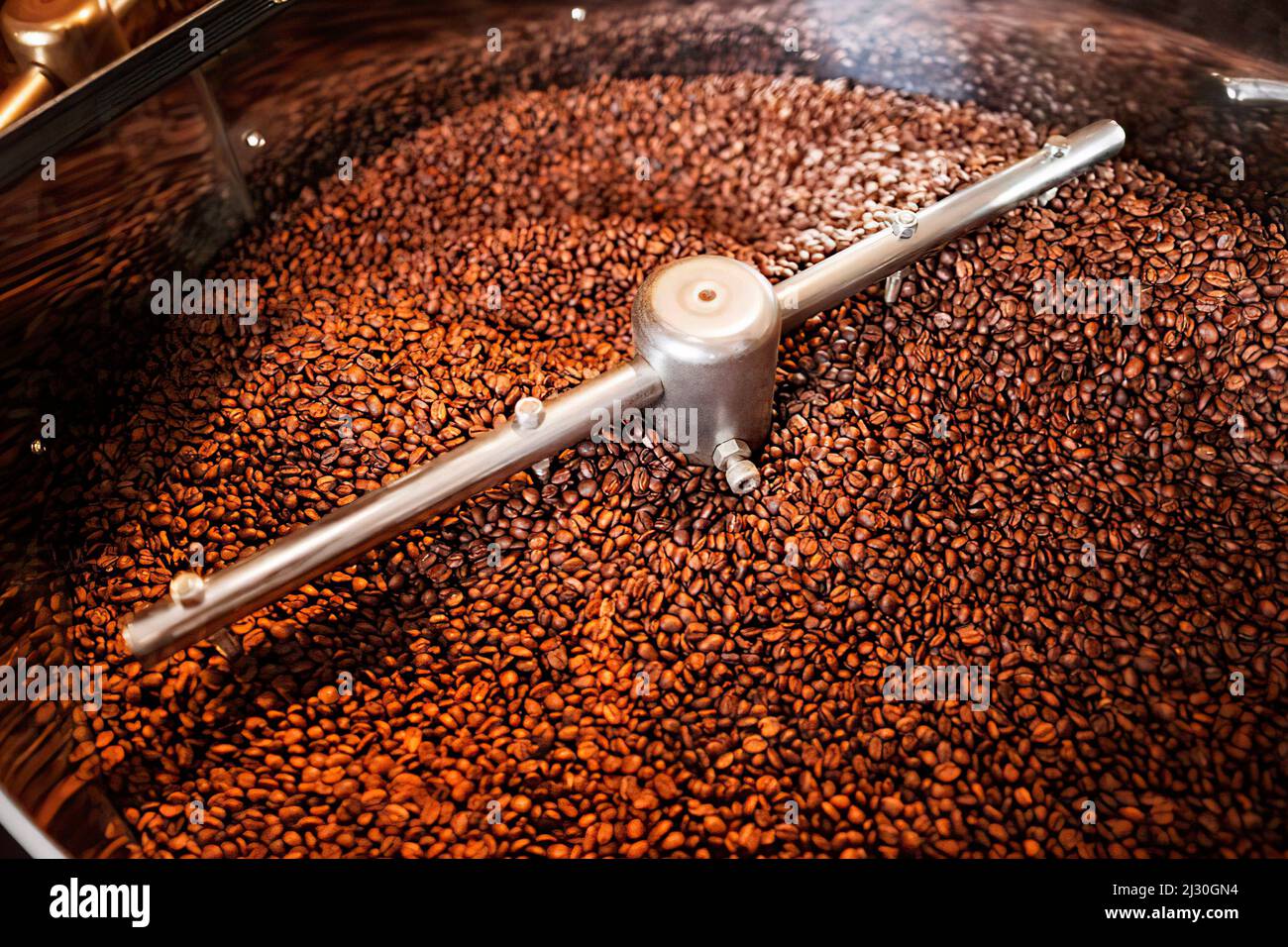 The freshly roasted coffee beans from a coffee roaster are mixing in