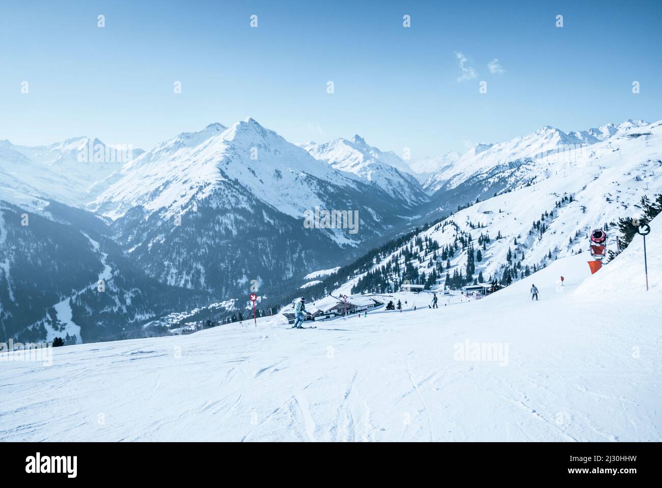 Skiers skiing on snow covered mountain slope against blue sky Stock Photo