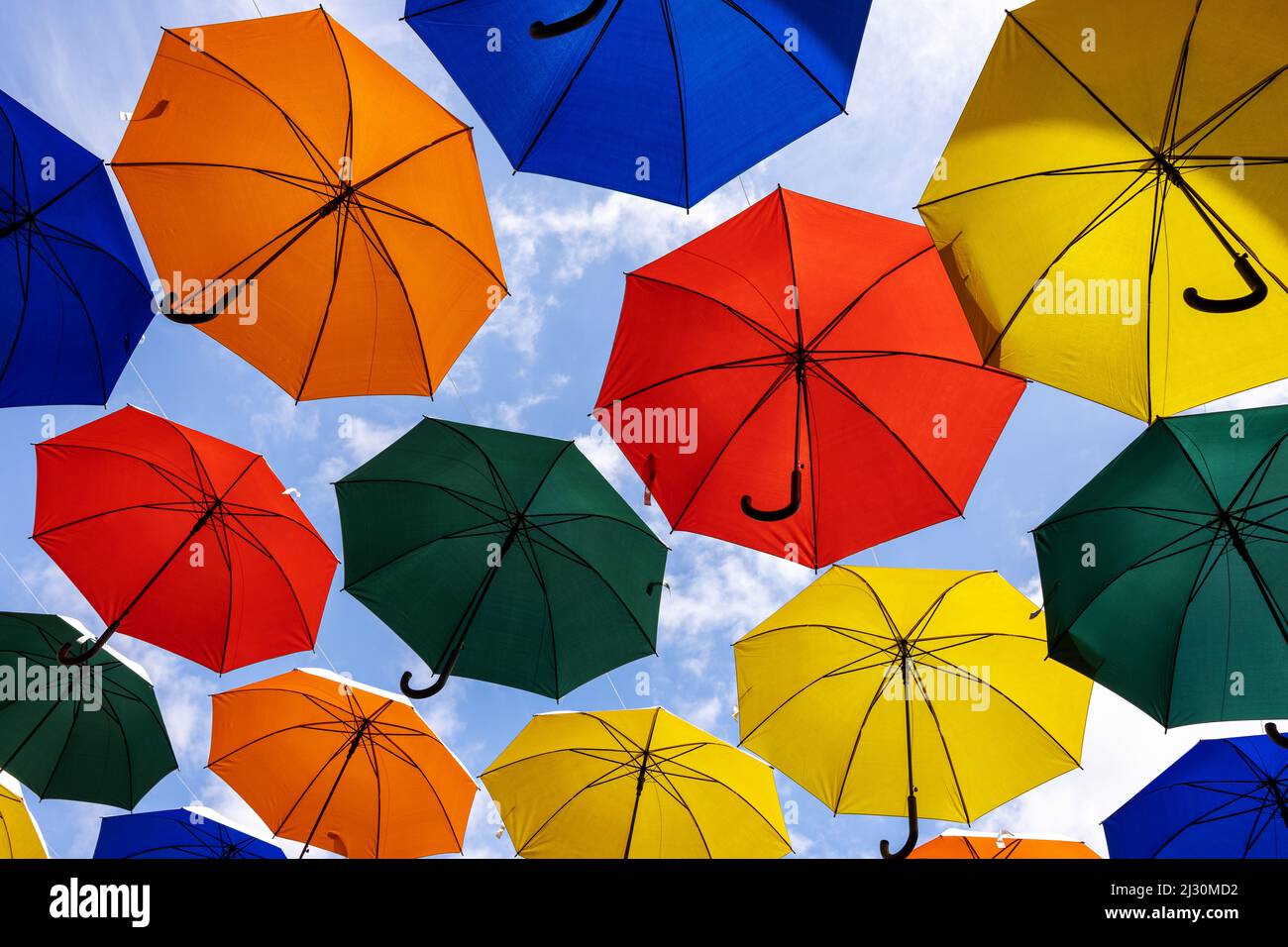 colorful umbrellas hanging against blue sky. city street art Stock Photo