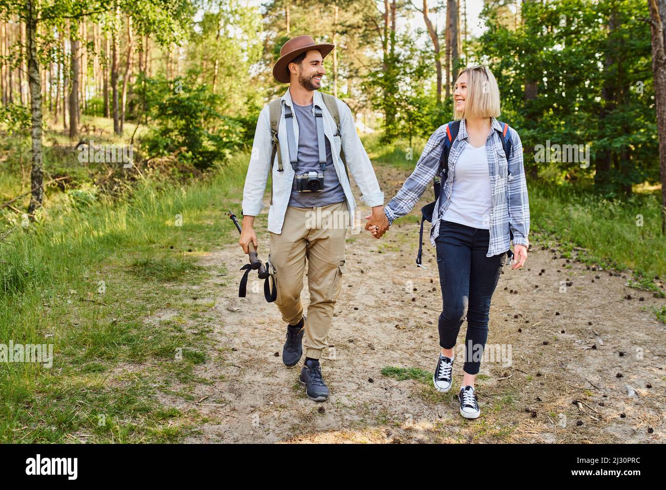 Young couple walking together in the woods holding hands Stock Photo ...