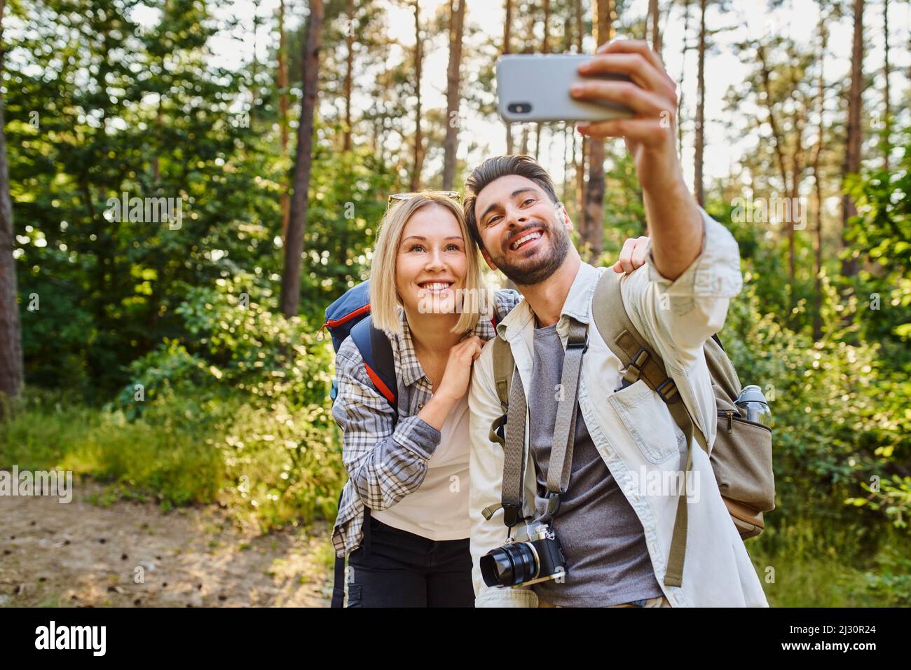 Young couple taking selfie picture with smartphone while hiking in the ...