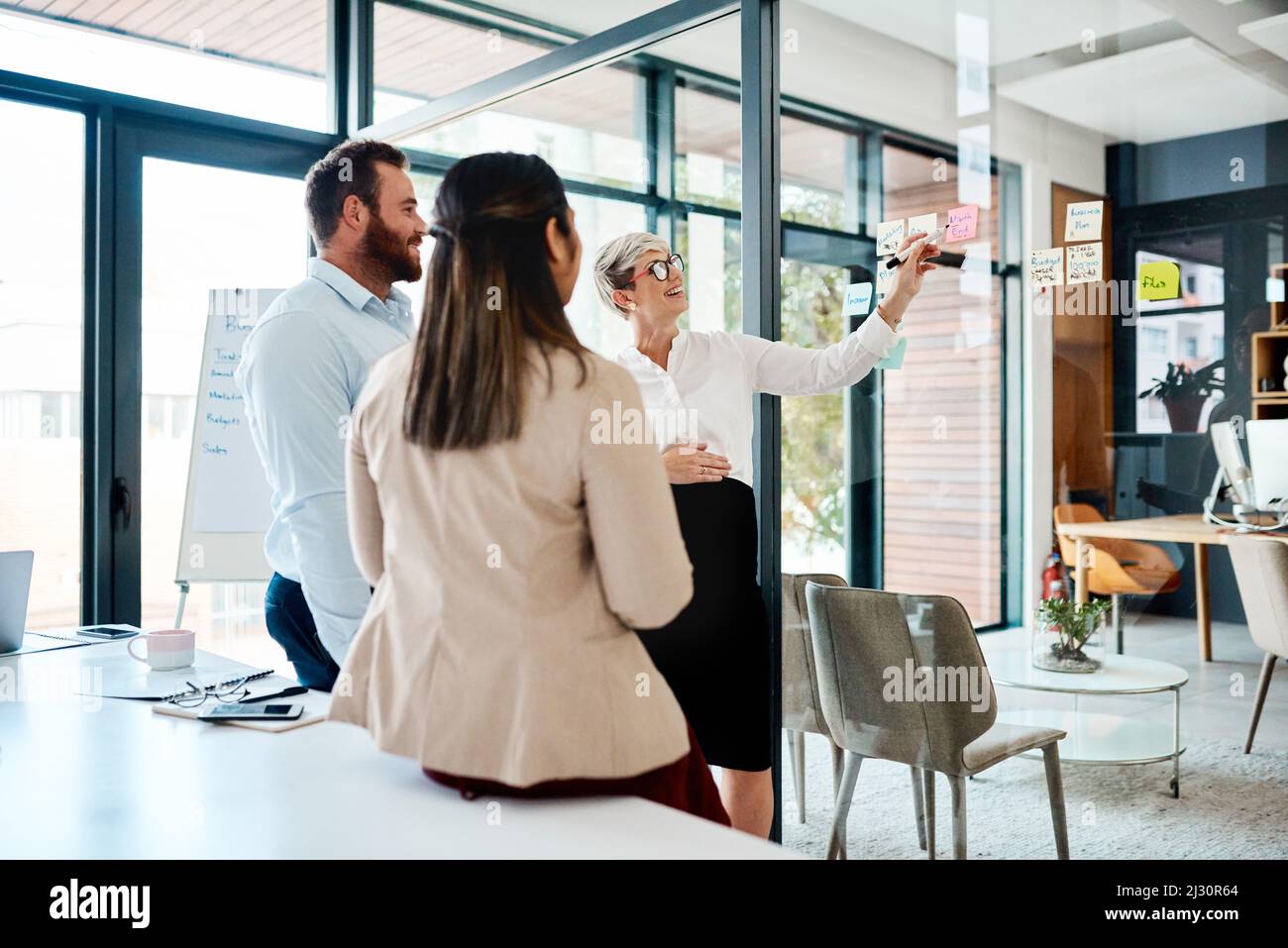 Brainstorming sessions thatll make a big difference. Shot of a group of businesspeople brainstorming with notes on a glass wall in an office. Stock Photo