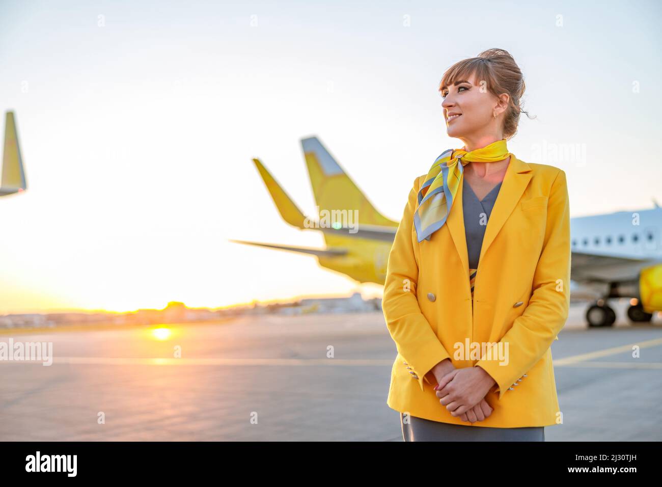 Joyful woman flight attendant standing outdoors at airfield Stock Photo