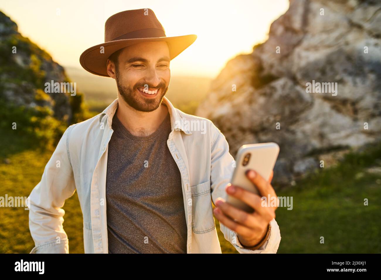 Young man using smartphone during summer hike in mountains Stock Photo