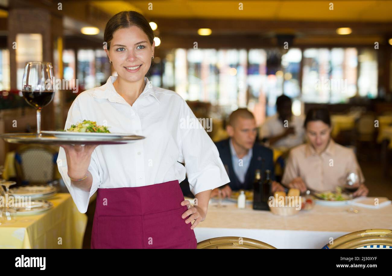 Professional attractive female waiter holding serving tray Stock Photo